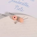 Macro view of 10mm pink striped wooden beads with silver metal pin on a ceramic plate - Pink