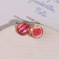 Close-up of round resin earrings with red swirling texture and gold metal edges - Red