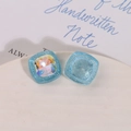 Dettaglio macro di ciondoli quadrati in resina glitterata celeste con strass iridescenti - Blu con Zirconia Bianca