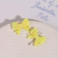 Detailed macro view of yellow resin bow charms with pearlescent finish and metal pin back - Yellow