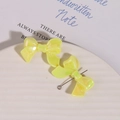 Detail of yellow iridescent bow charms with pearlescent finish in a white ceramic dish - 1 Piece/Pack / Yellow