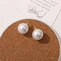 Macro shot of round cream white pearl pendants with gold rings on a cork coaster - 18mm