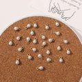 Close-up of DIY pearl pendants with gold rings for jewelry making on a cork surface - 4mm