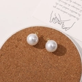 Close-up of white round faux pearl charms with gold loops for DIY jewelry making - 14mm