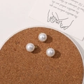 Close-up of three 10mm white faux pearl pendants with gold loops for DIY jewelry making - 10mm