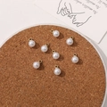 Flat lay of imitation pearl pendants with gold loops on a cork mat for DIY jewelry - 6mm