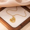 Détail d'un collier coeur doré avec lettrage MOM sur fond de soie couleur champagne - Collier Cœur 'MOM' (0822)