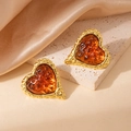 Primer plano detallado de pendientes de corazón dorados con ámbar sobre seda - Corazón Martillado Piedra Marrón Pendiente 1984