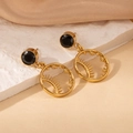 Detailed close-up of golden sun and star earrings with black stones on marble surface - Black Zirconia Sun Star Style (2002)