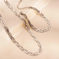 Gros plan d'un ensemble collier et bracelet tressés en acier sur tissu de soie - Collier Argenté (0090)