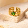 Macro view of gold braided ring featuring a green stone on natural stone background - Braided Green Cat's Eye Adjustable Style (TYR0833)