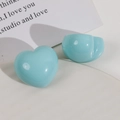 Close-up of light blue glossy resin heart and round charms on a white decorative tray - Green Heart