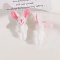 Close-up of cute plush bunny charms with pink heart stitching on a white ceramic plate - White