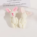 Detail view of two soft plush bunny charms with pink embroidered ears and white loop cords - Beige