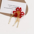 Detailed close-up of handmade beaded red flower accessory with golden beaded tassels - Red One Piece
