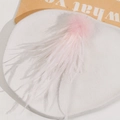 Close-up of a soft pink feather accessory with a fluffy pompom on a stone pedestal - Pink