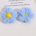 Makro-Detail von handgehäkelten, flauschigen fünfblättrigen Blumen in Himmelblau und Gelb - Blau