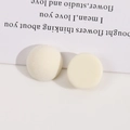 Primo piano di orecchini tondi asimmetrici con velluto crema e finitura in resina liscia - Bianco