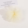 Dettaglio dell'elastico per capelli a fiore in organza gialla su cartoncino bianco - Beige