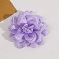 Detailed macro view of a multi-layer purple satin camellia flower fabric accessory - Purple