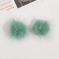 Close-up of mint green faux mink fur pom-poms for DIY jewelry and hair accessories - Verdant