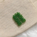 Pendentif Xi en résine verte avec sculpture creuse sur fond de lin rustique - Carré Vert