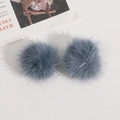 Detailansicht zweier graublauer Webpelz-Pompons für DIY-Haarschmuck und Bastelbedarf - Graublau