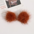 Nahaufnahme von zwei braunen Nerzfell-Pompons für DIY-Haarschmuck und Kleidung - Orange