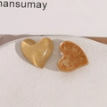 Macro detail of heart-shaped resin jewelry accessories with amber texture and gold finish - Yellow
