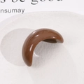 Pince à cheveux demi-lune en résine marron polie présentée sur une assiette blanche épurée - Café Foncé