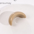 Détail d'une pince à cheveux en résine en forme de croissant kaki sur plat blanc - Café Clair