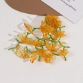 Close-up of handmade beaded floral accessory with orange resin petals and green leaf beads - Orange