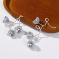 Macro detail of handmade beaded earrings with grey lotus petals and branch-like beads - Gray