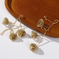 Handgefertigte goldene Perlenohrringe mit Blumenmuster auf einem Holztablett - Goldgelb