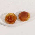 Detailed macro view of amber resin flower charms with glossy finish and sand texture - Brown