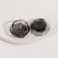Detail macro shot of smokey black resin rose earrings with marble texture on ceramic plate - Black
