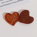 Detail of amber heart resin charms with translucent ripple and gold glitter textures - Brown