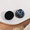 Makro-Detail von 20mm runden AB-Harz Cabochons mit bunten Glitzer-Effekten auf Schwarz - Schwarz
