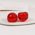 Détail macro de perles en résine rouge translucide sur plateau blanc pour DIY - Rouge