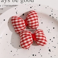 Close-up of red and white checkered bow hair clips on a decorative white ceramic tray - No Accessories / Gingham