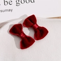 Detail of two handmade deep red velvet bow hair clips on a white ceramic plate - Burgundy
