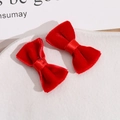Close-up of a pair of red velvet handmade bow hair clips on a white ceramic plate - Red