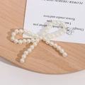 Macro shot of pearl bow charm with an engraved Believe in Serendipity silver metal disk - Silver