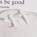 Close-up van twee handgemaakte witte strikken op een bord voor DIY-sieraden maken - Wit