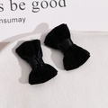 Close-up of elegant black velvet hair bows with ribbon centers on a white ceramic plate - Black