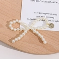 Detailed view of a white pearl bow charm with a vintage gold metal disc pendant - Gold