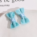 Detail of light blue velvet ribbon bows with metal snaps and soft texture on a white plate - Blue