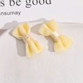 Primo piano di un paio di morbidi fiocchi in velluto crema su un piatto bianco - Giallo