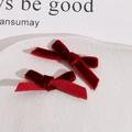 Close-up of two handmade dark red velvet bow hair clips on a ceramic tray display - Burgundy