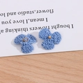 Makroaufnahme von hellblauen Strickblumen mit goldenen Metallringen und Perlen für DIY - Saphirblau